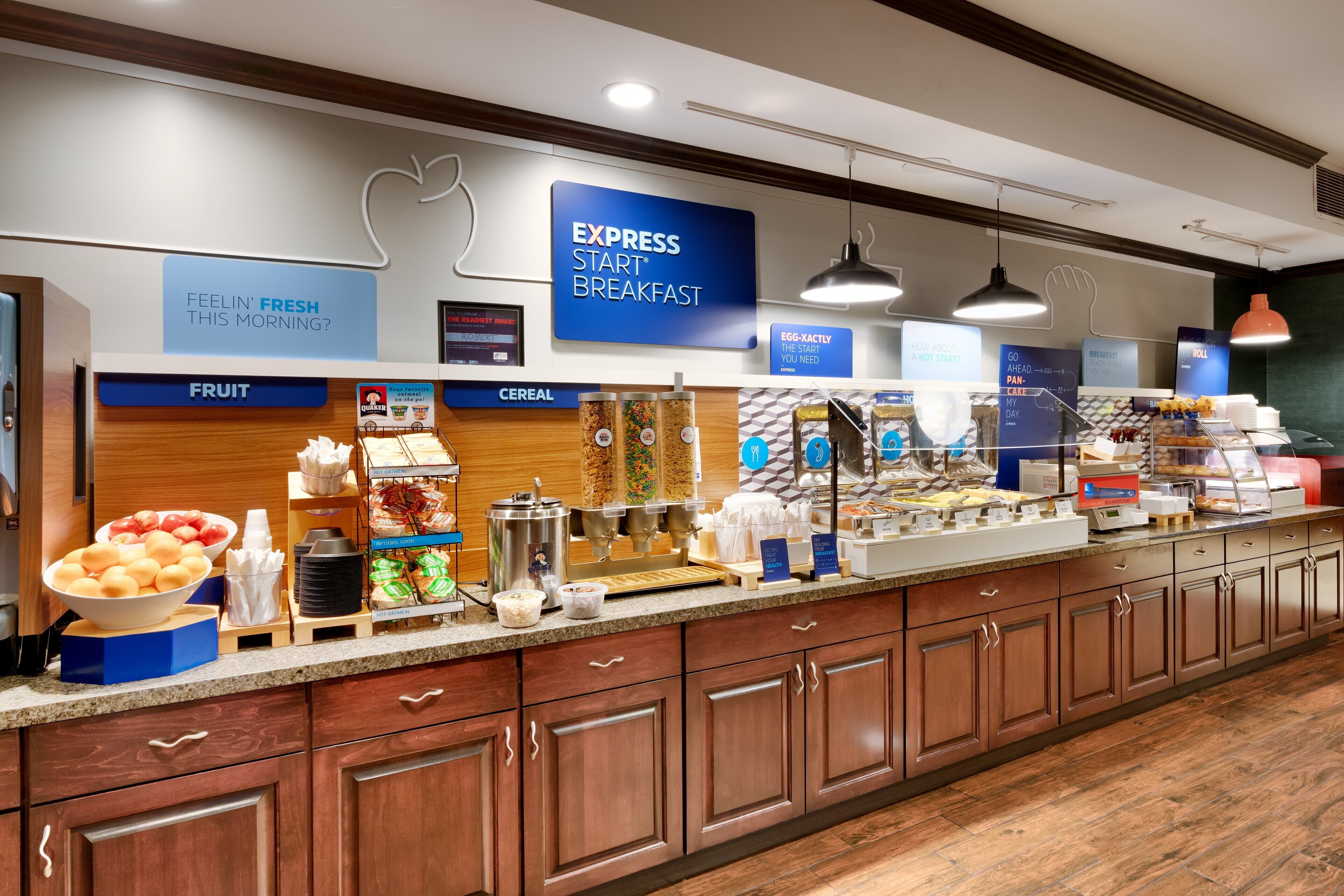 A breakfast bar with labeled sections for fruit, cereal, and a sign for express breakfast.