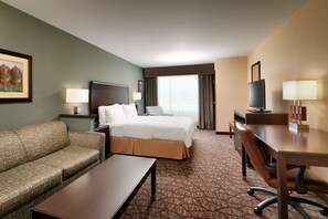 A hotel room with a bed, a sofa, a desk, and a television.