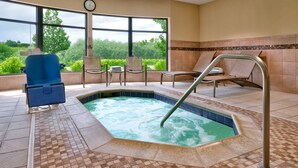 Une chambre d’hôtel avec une grande fenêtre, un jacuzzi et plusieurs fauteuils.