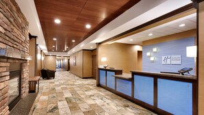 Un hall d’hôtel comprenant un comptoir d’accueil, une cheminée et un guichet pour l’enregistrement des clients.