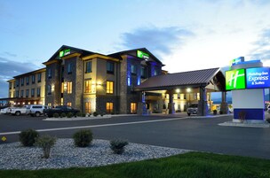 Un hotel Holiday Inn Express con fachada de piedra, varias entradas y un estacionamiento.