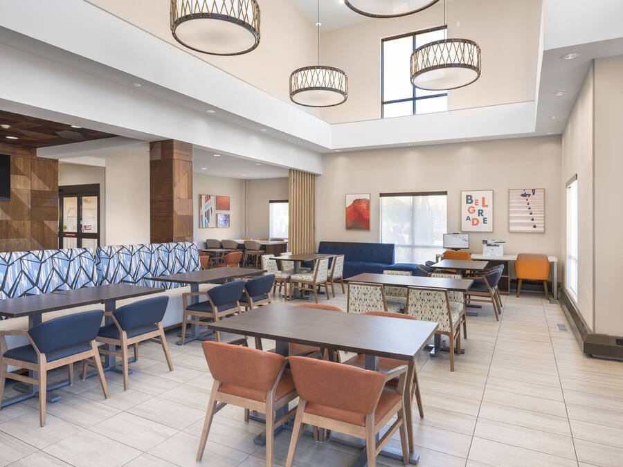 A spacious indoor area with multiple seating arrangements including tables and chairs, a large sofa, and a television mounted on the wall.