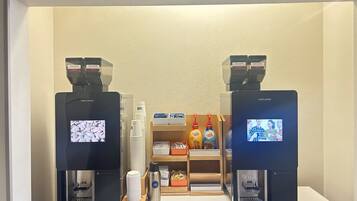 A coffee bar with two coffee machines, disposable cups, and a coffee dispenser.