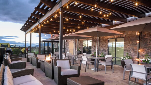 An outdoor patio with wicker furniture, stone walls, and string lights. - Holiday Inn Express Hotel & Suites Belgrade by IHG (Belgrade)