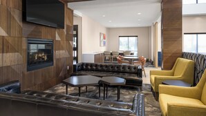 A modern lounge area with a fireplace, leather seating, and a flat-screen TV. - Holiday Inn Express Hotel & Suites Belgrade by IHG (Belgrade)