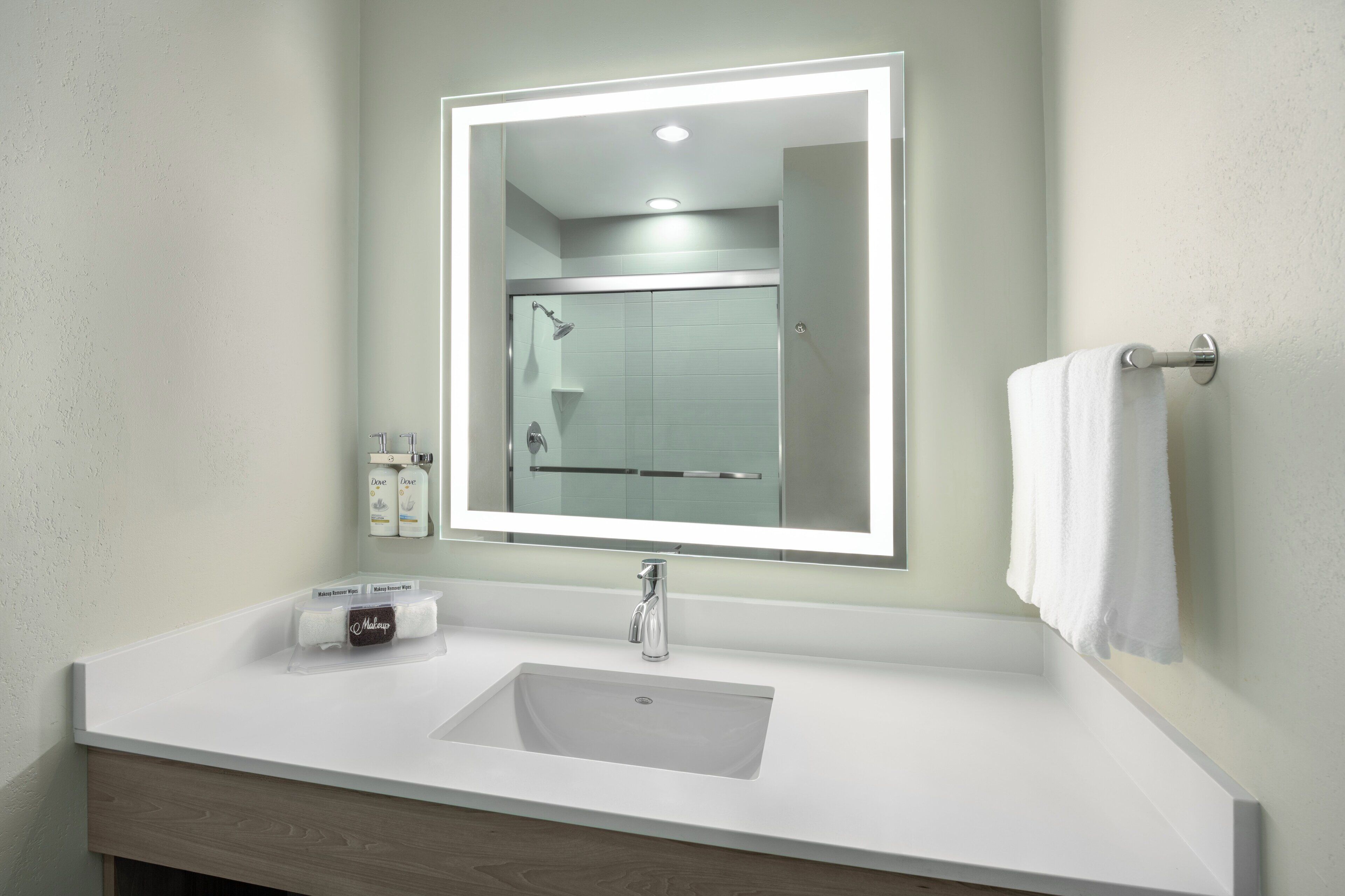 A bathroom with a white sink, a mirror, and a towel rack.