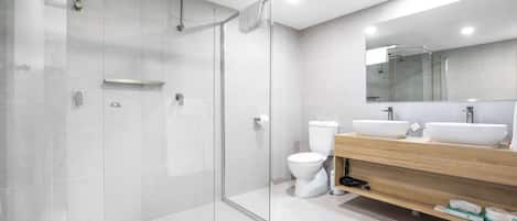 Un baño moderno con cabina de ducha de vidrio, inodoro y tocador doble.