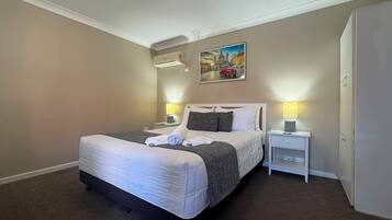Quarto de hotel com cama, duas mesas de cabeceira, um quadro na parede e uma luminária de teto.