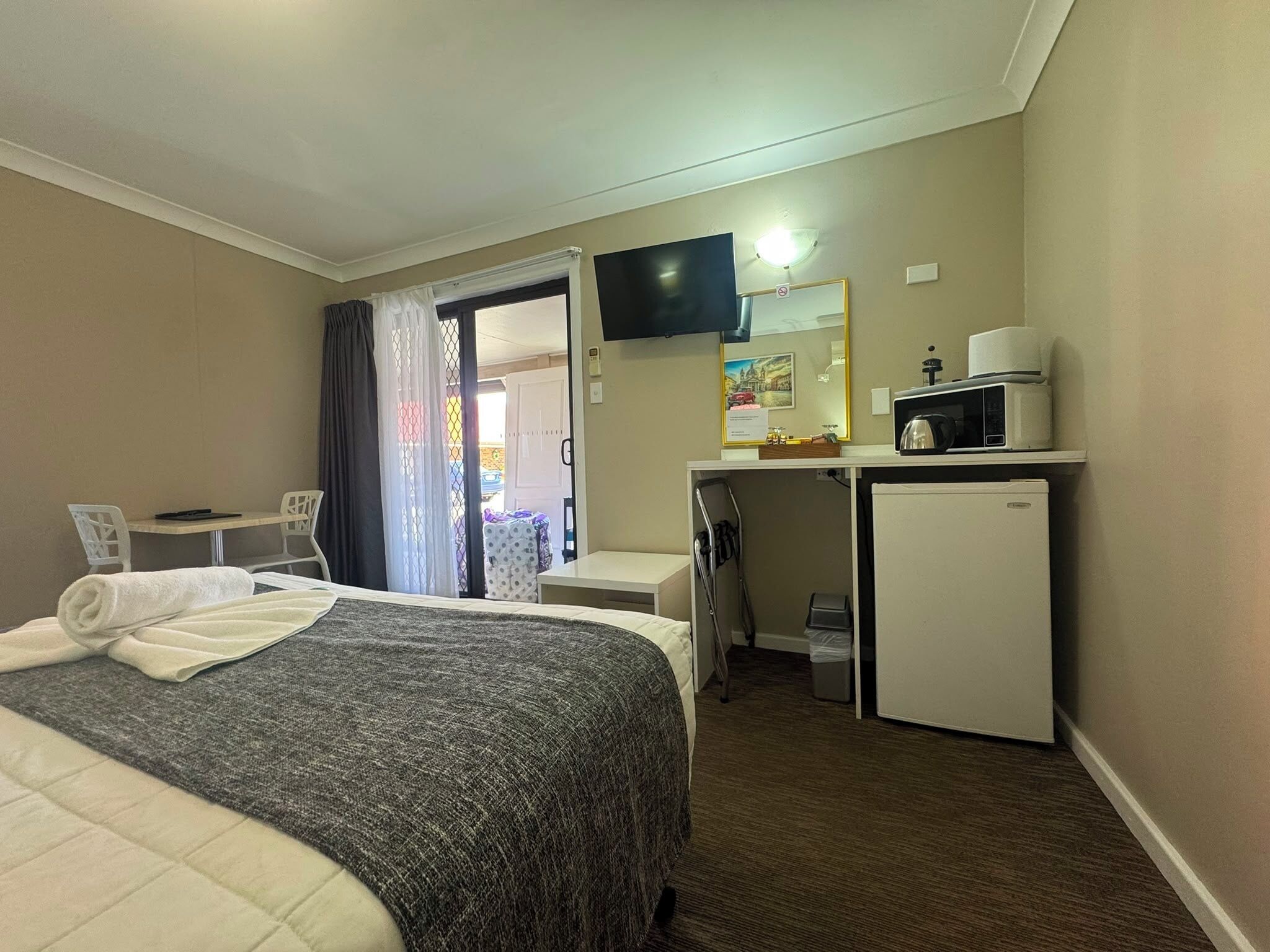 Een hotelkamer met een bed, een bureau, een televisie, een magnetron en een koelkast.