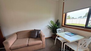 A room with a beige sofa, a white table, and a potted plant.