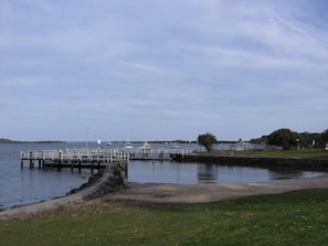A waterfront dock with a grassy area in the foreground and a clear sky.