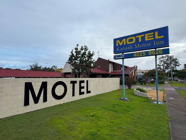 A motel sign with the name 'Karun Motor Inn' and a contact number.