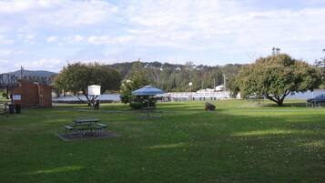 A park with picnic tables, a shelter, and a lake in the background.