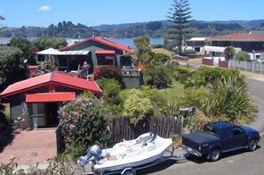 A residential area with houses, a boat, and a truck. - Moanarua Beach Cottage (Ohope)