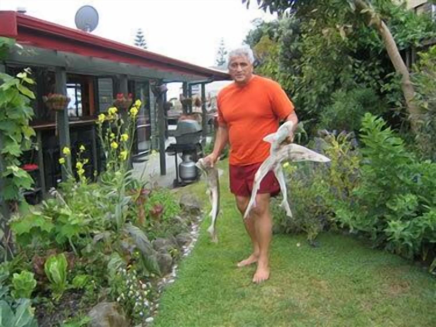 A person standing in a garden with a house in the background.