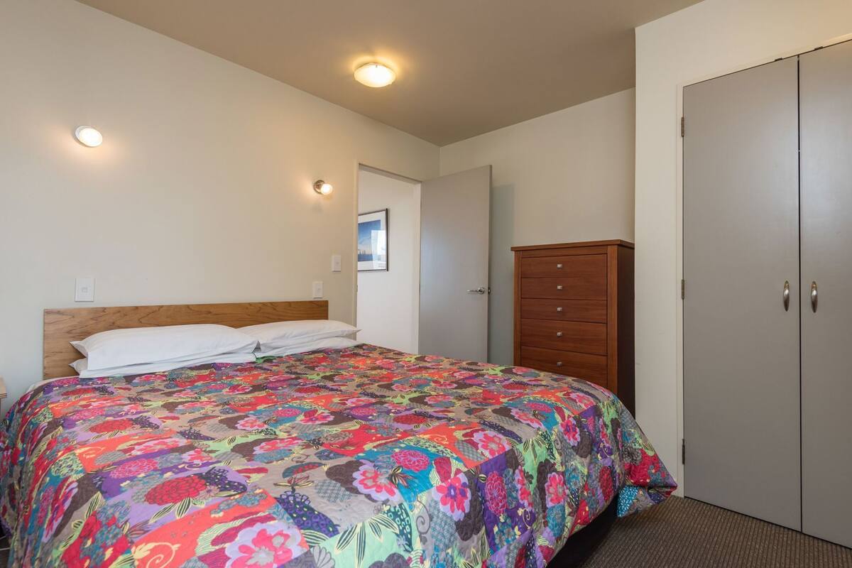 Un dormitorio con una cama, cabecera de madera, cómoda y armario.