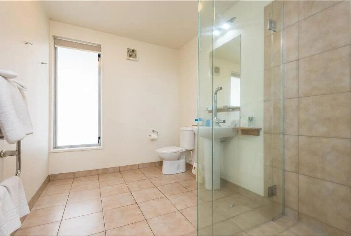 Een badkamer met toilet, wastafel en een douchecabine van glas.