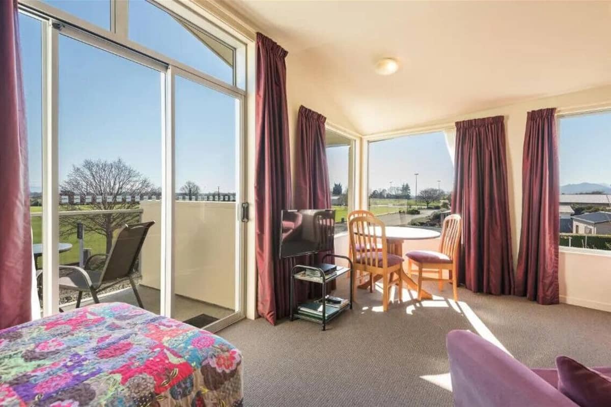 Una habitación con cama, una mesa y sillas, y vistas al exterior.