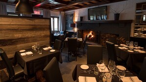 Un restaurante con paredes de madera, chimenea y mesas dispuestas para comer.