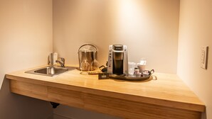 Una encimera de cocina con un fregadero, una cafetera y un hervidor.