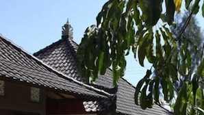 A building with a tiled roof, a glass entrance, and a small garden area with a pathway. - Baruna Cottages (Kintamani)