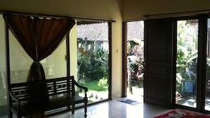 A room with a bench, a large window, and a door leading outside. - Baruna Cottages (Kintamani)