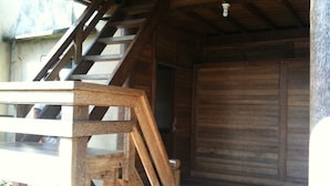 A wooden staircase leading to a room with a wooden door. - Baruna Cottages (Kintamani)