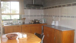 A kitchen with wooden cabinets, a round table, and a window. - Hostal Pukao (Hanga Roa)