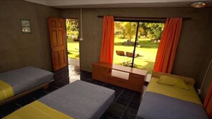 A room with two beds, a wooden cabinet, and a window with curtains. - Hostal Pukao (Hanga Roa)