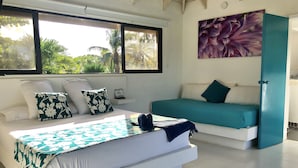 A bedroom with a large bed, a smaller bed, and a window with a view of greenery. - Hotel Casa De Las Flores (San Andrés)