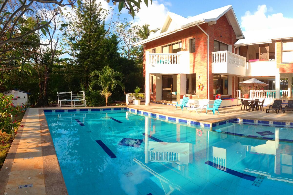 Un bâtiment à deux étages doté d’une piscine, d’un espace extérieur aménagé et d’un hamac.