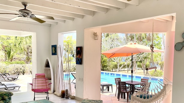 A spacious indoor area with a ceiling fan, a poolside seating area, and a view of a swimming pool. - Hotel Casa De Las Flores (San Andrés)