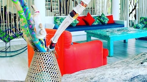 A modern interior with a ceiling fan, a colorful woven sculpture, a red sofa, and a blue bench. - Hotel Casa De Las Flores (San Andrés)
