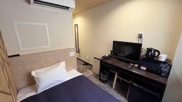 Ein Hotelzimmer mit einem Bett, einem Schreibtisch mit Fernseher, einer Mikrowelle und einer Kaffeemaschine.