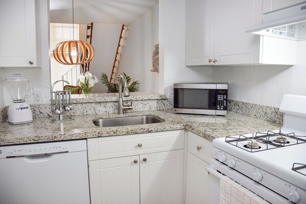 A modern kitchen with white cabinets, a granite countertop, a built-in microwave, a gas stove, and a dishwasher. - Coral Reef at Key Biscayne (Key Biscayne)