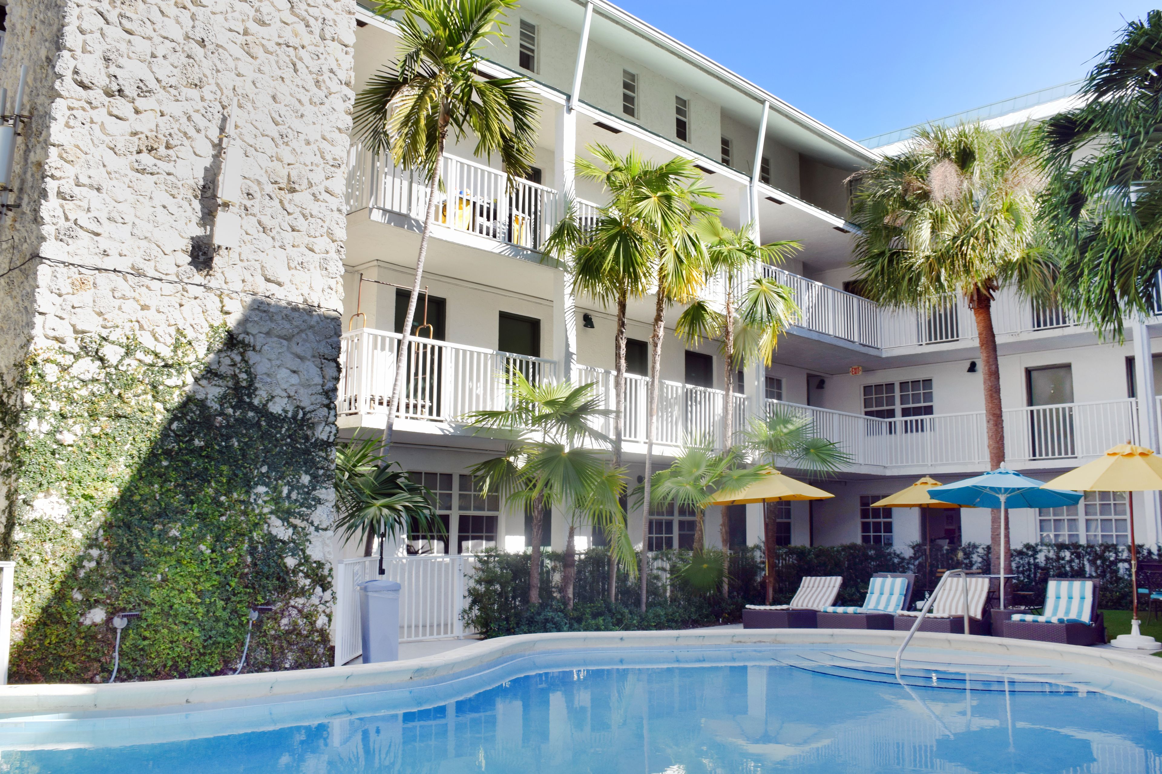 Un hotel con piscina, varios balcones y palmeras.