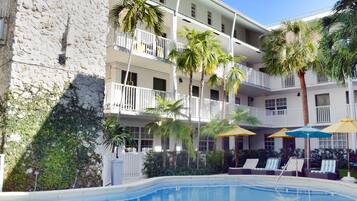 Un hotel con piscina, varios balcones y palmeras.