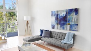 En moderne stue med en grå hjørnesofa, et hvidt sofabord og abstrakte malerier på væggen.