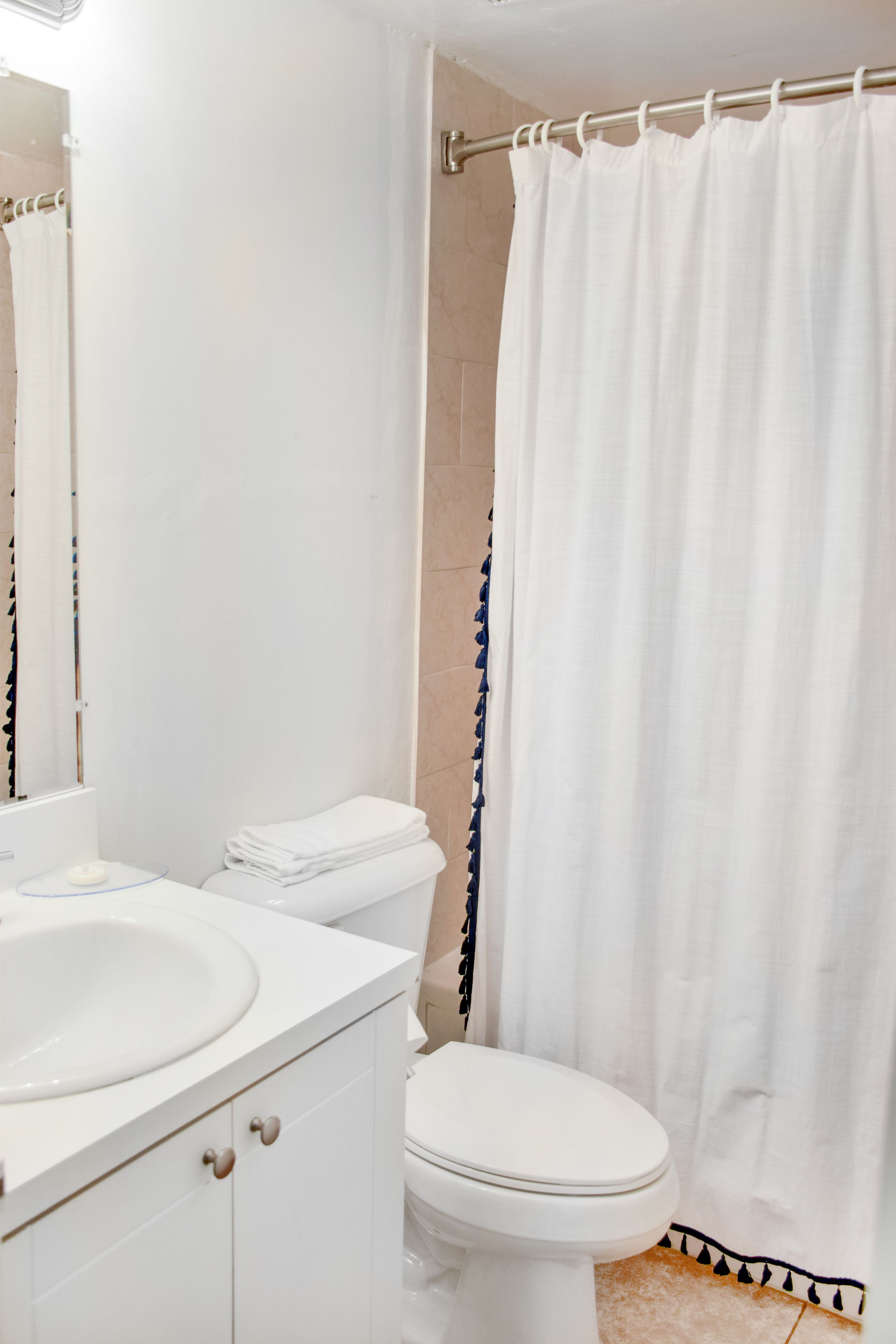 A bathroom with a white sink, toilet, and shower curtain.