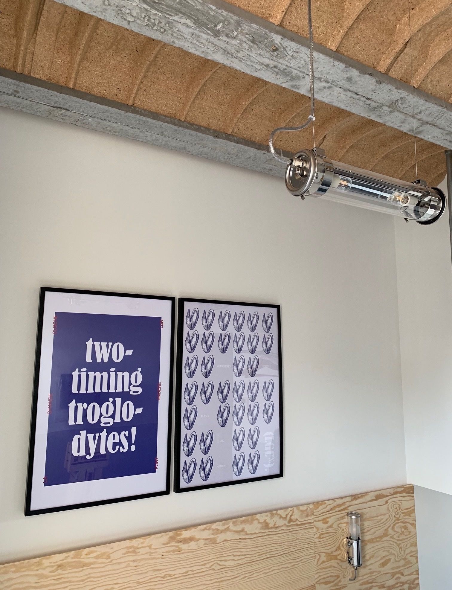 Een kamer met een houten plafond, een kunstwerk met tekst in een lijst, en een behang met patroon.