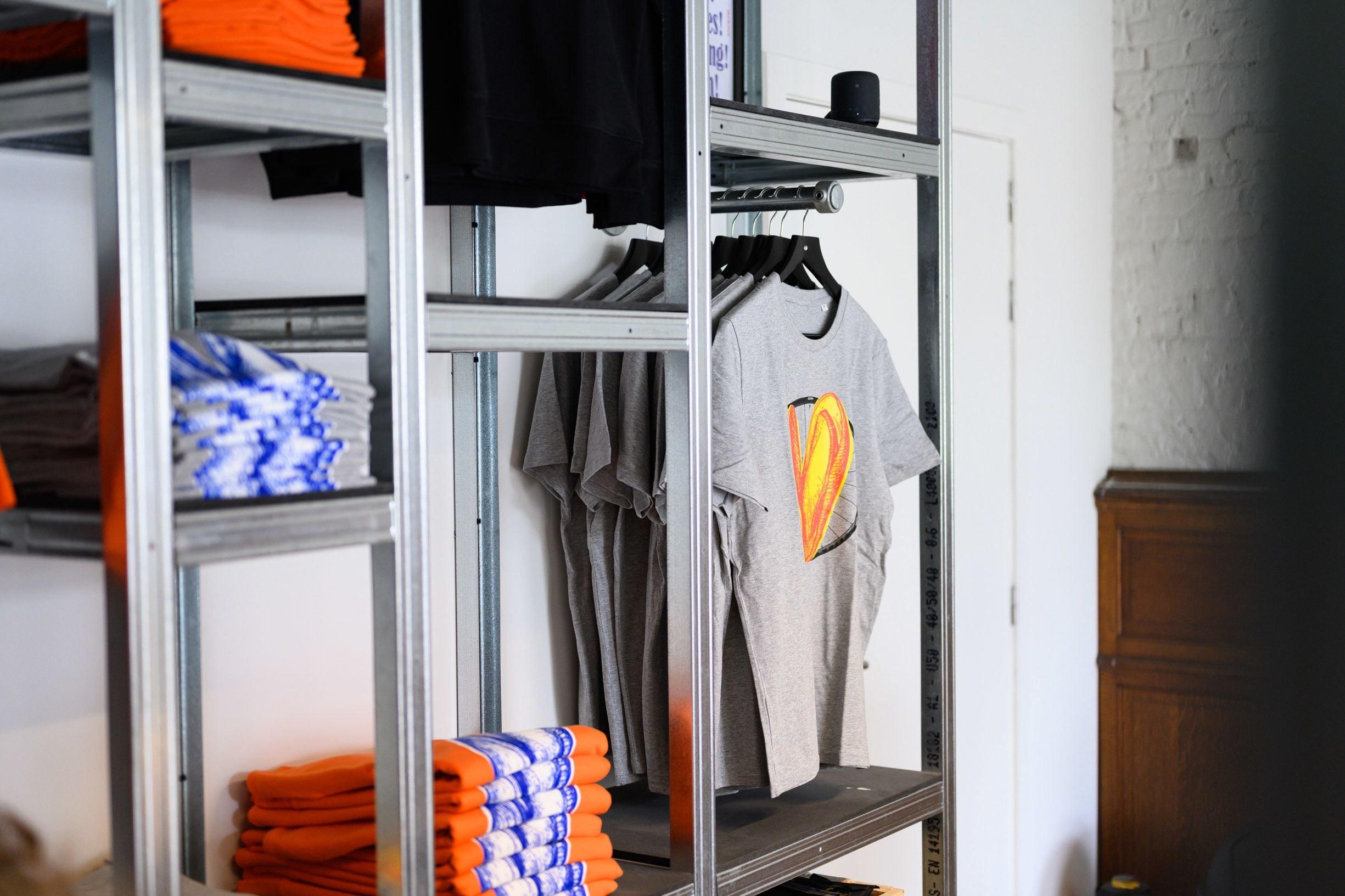 Un perchero con ropa doblada y una camiseta con diseño gráfico.