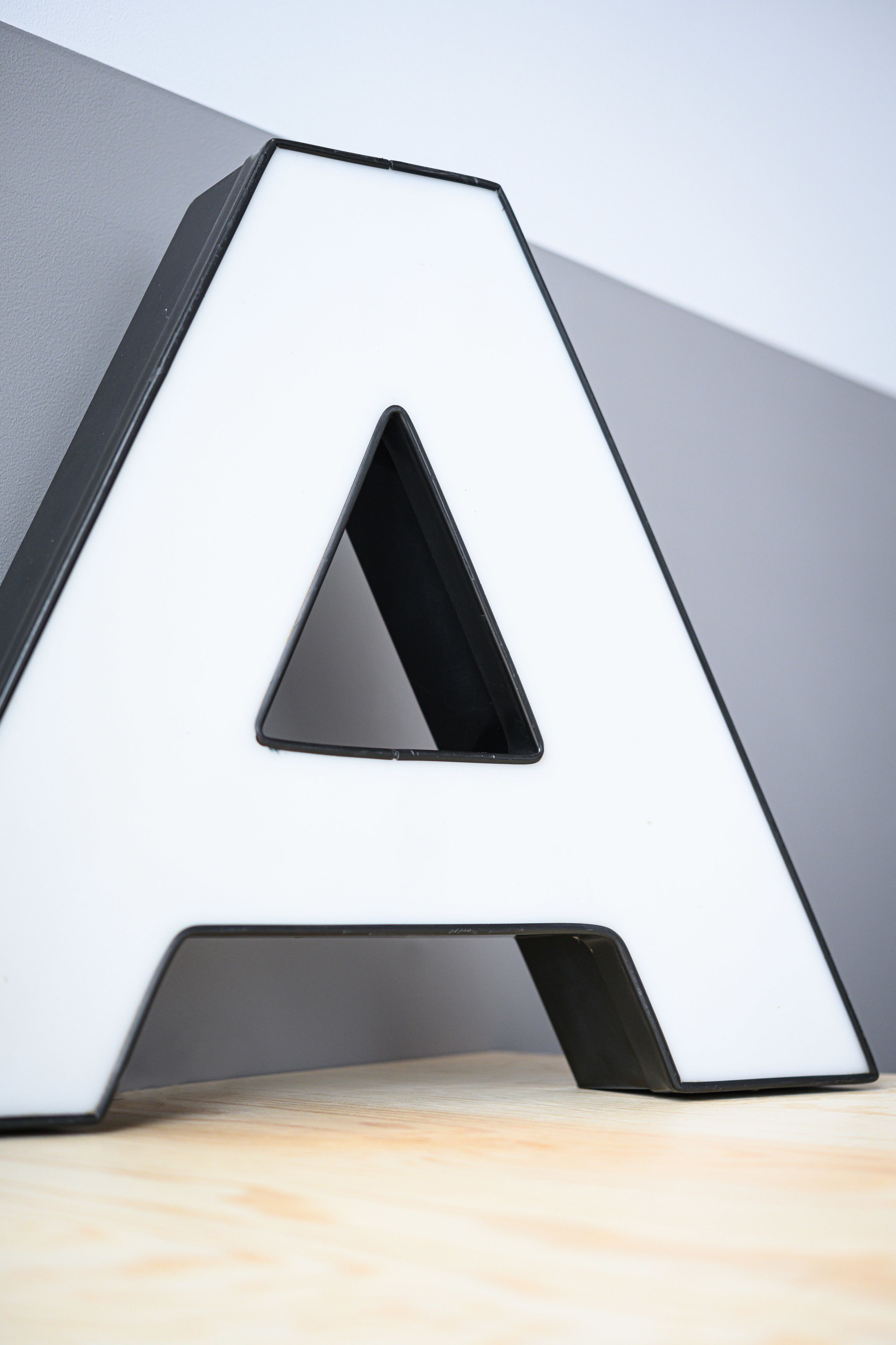 A white, angular letter A-shaped object on a wooden surface.