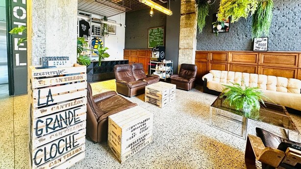 A modern lounge area with leather sofas, wooden crates, and hanging plants. - Hotel La Grande Cloche (Brussels)