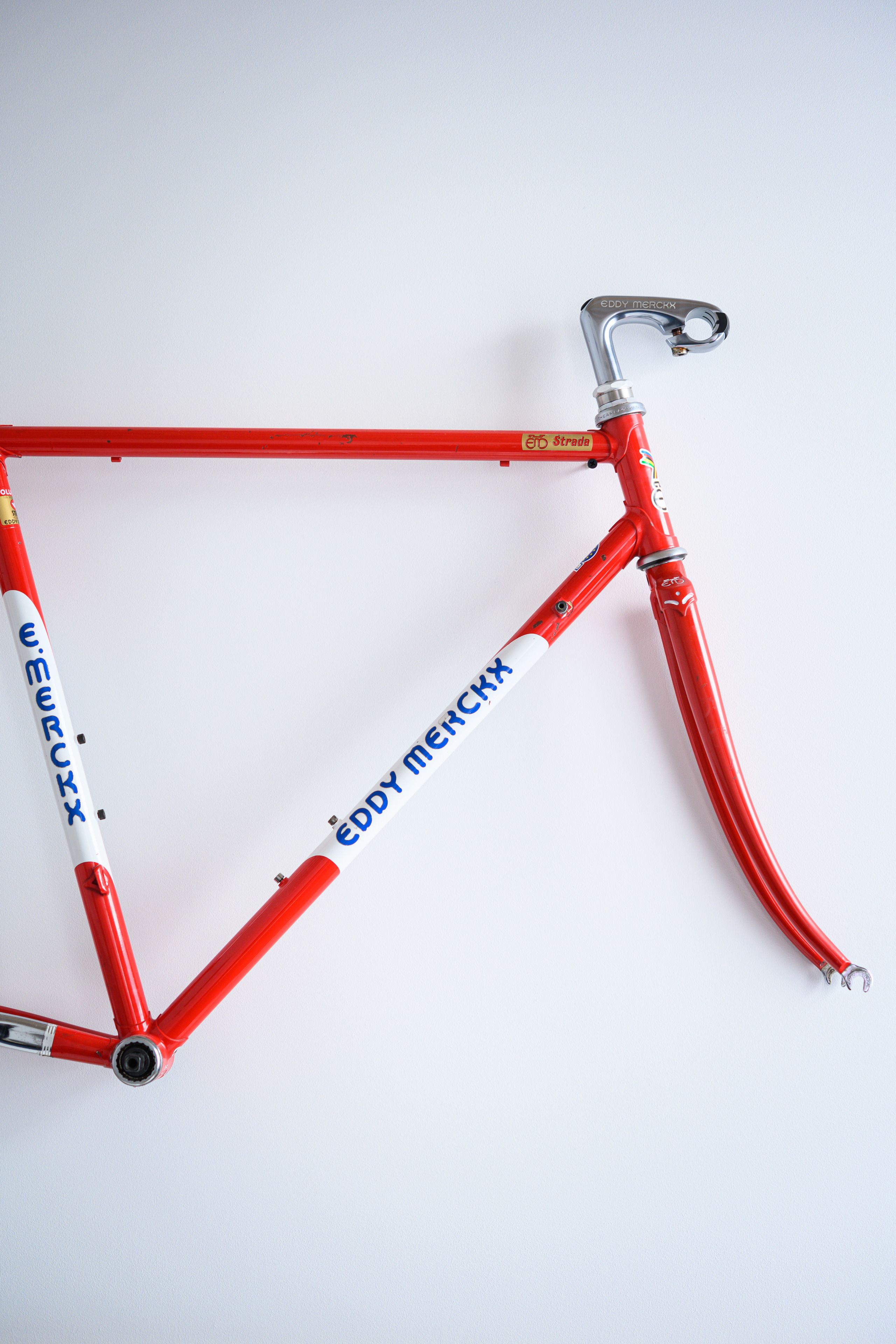 Een rode fiets met de merknaam 'Eddy Merckx'.
