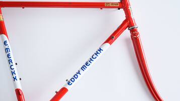 Een rode fiets met de merknaam 'Eddy Merckx'.