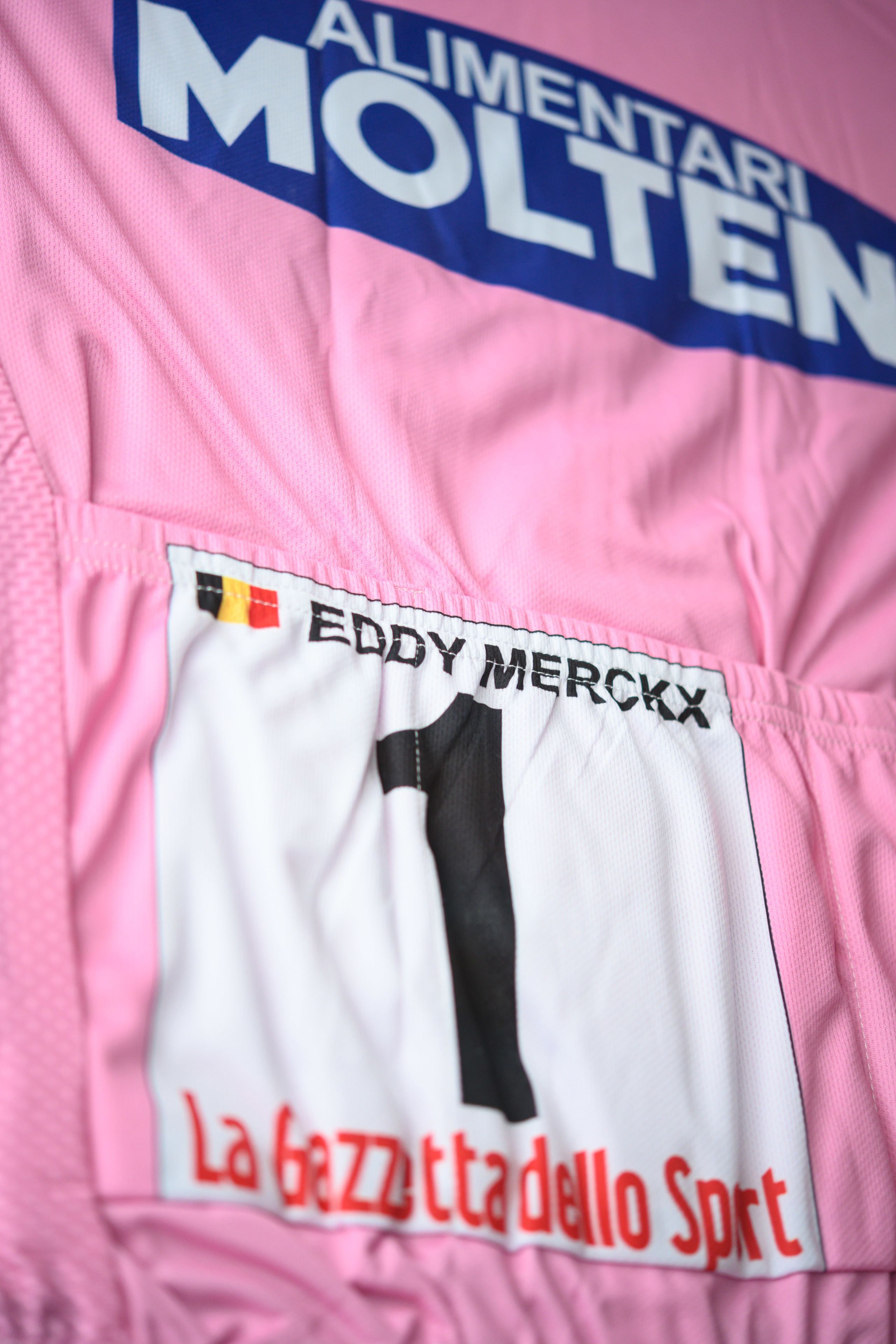 Een close-up van een sportshirt met de tekst 'ALIMENTARI MOLTEN' en 'EDDY MERCKX' erop.