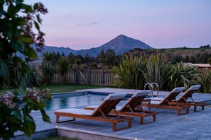 A pool area with lounge chairs and a wooden deck. - Wanaka Haven (Wanaka)