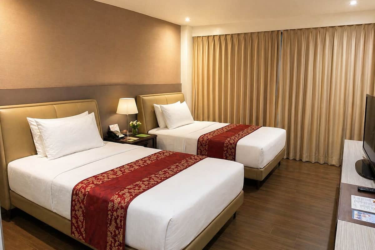 A hotel room with two beds, a desk with a TV, a lamp, and a phone on the nightstand.