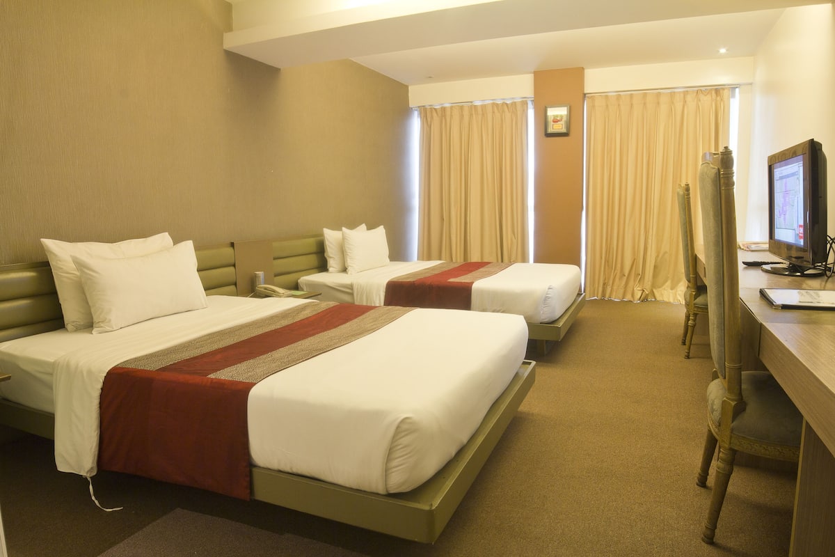A hotel room with two beds, a desk with a computer, and a television.