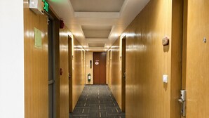 A hotel hallway with wooden doors, a patterned carpet, and an exit sign. - The E-Hotel Makati (Makati)